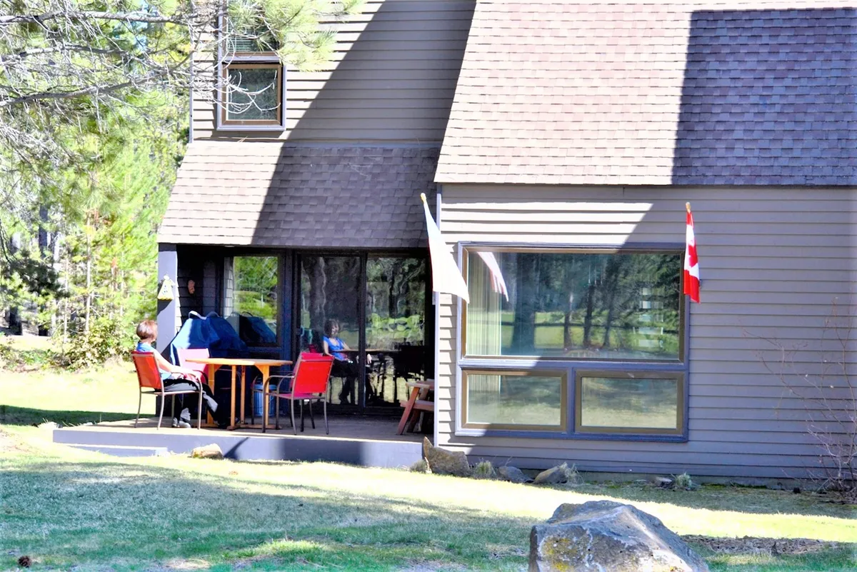 An outdoor dining table on a welcoming porch, with a view out to a well-kept outdoor space. The scene suggests opportunities for casual meals, relaxation, and social gatherings in a pleasant setting.