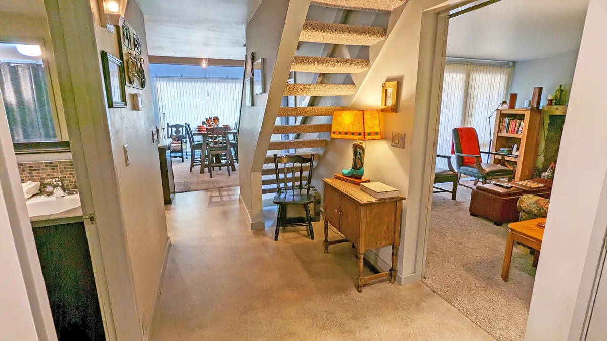 A spacious, cozy area with a visible staircase, wooden furniture, a lamp, and inviting decorative touches on the walls. The layout suggests ample room for family gatherings, socializing, and relaxing after a day of adventure.