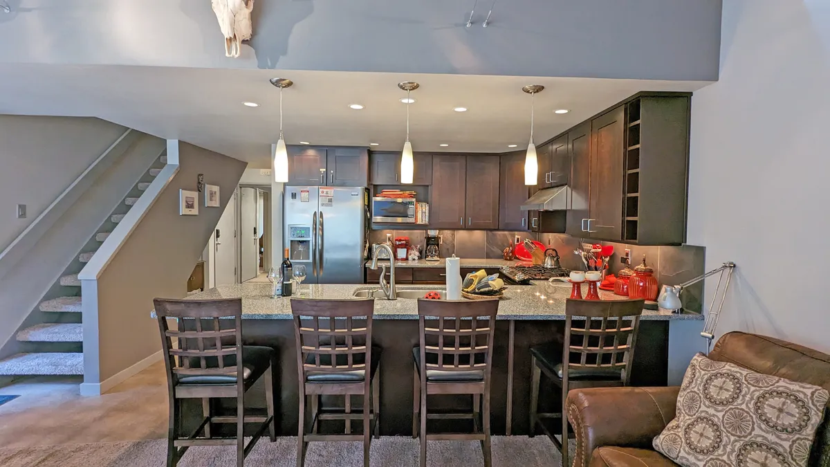 A modern kitchen with a large island, bar stools for casual seating, and stainless steel appliances. The space is designed for cooking together, entertaining, and enjoying family-style meals, with thoughtful lighting and decorative accents.